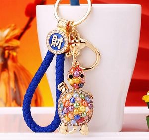 Detail of crystal turtle keychain with blue woven rope and fortune coin charm