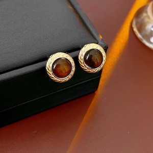 Nahaufnahme von runden Vintage-Ohrringen aus Harz in Goldfassung auf einer Geschenkbox
