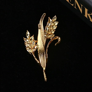 Macro shot of gold wheat brooch with amber crystals on black velvet background