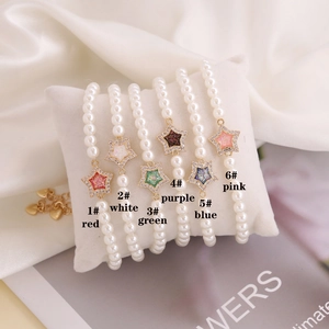 Detailed view of six pearl bracelets with colorful star charms on a white display pillow