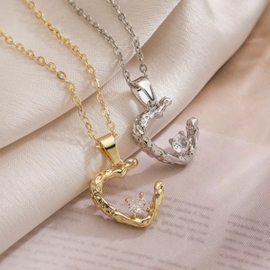 Gold and silver irregular heart pendants with zircon on beige silk fabric background