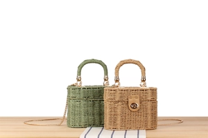 Close-up of woven straw bags with golden twist-lock and chain straps in olive and beige