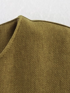 Macro shot of olive green corduroy fabric showing detailed ribbed texture and fine stitching
