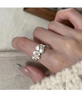 Macro shot of three white matte flower rings with gold centers on a soft sweater