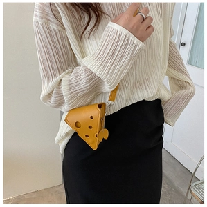 Detailed view of cheese-shaped yellow crossbody bag worn by a model with golden chain strap