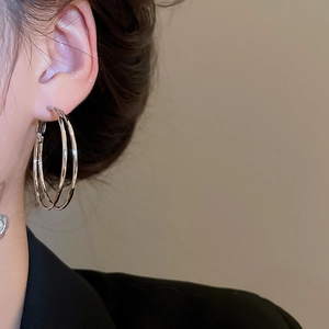 Close-up of silver-tone double hoop earrings with a polished metallic finish on ear