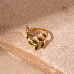 Macro detail of vintage gold-tone ring featuring green oil-dripped leaf texture and design