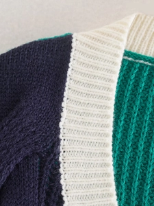 Dettaglio del cardigan in maglia tricolore con texture blu navy, bianco e smeraldo