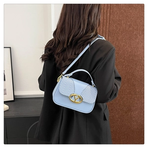 Close-up of women's blue crossbody bag with herringbone flap and gold V-shaped buckle