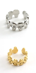 Close-up of punk skull rings in silver and gold steel finishes with adjustable open band