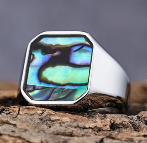 Detailed macro shot of rectangular abalone shell inlay on a silver stainless steel ring