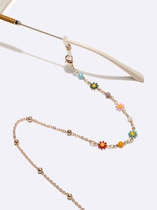 Détail de la chaîne de lunettes dorée avec perles florales colorées et boucles