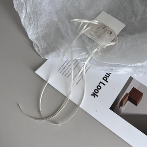 Detail of handmade bow hair clip with white ribbons and pearl beads on a book page