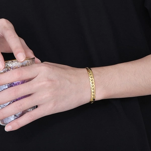 Minimalist golden stainless steel flat curb chain bracelet shown on a model wrist