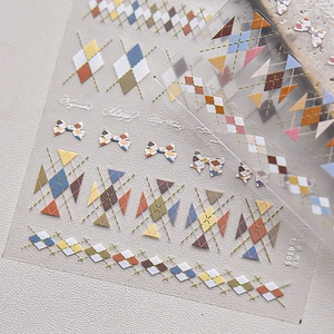 Colorful plaid nail stickers with bows and art lettering on a textured surface