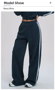 Detail view of navy blue wide-leg sports pants with white side stripes and pockets