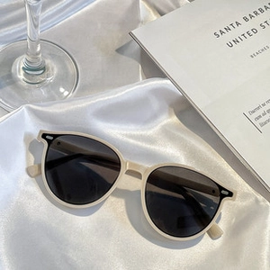 Detail view of foldable beige and black square sunglasses on white silk background