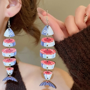 Detail view of ethnic fish bone earrings with wood print and red-blue tassel design