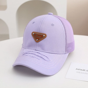 Dettaglio del cappellino viola in mesh con visiera usurata e stemma metallico a triangolo