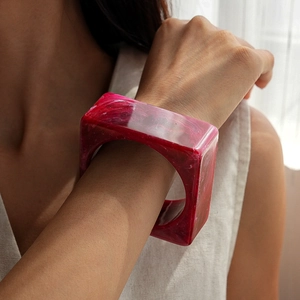 Detail shot of wide red marbled resin square bangle on model wrist with premium finish