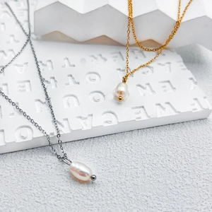 Close-up of gold and silver layered necklaces with natural freshwater pearls on a white background