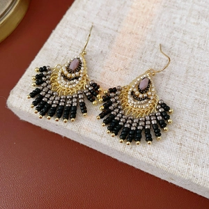 Detail of fan-shaped beaded tassel earrings in bohemian style on linen texture