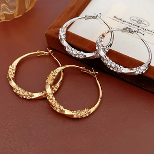 Twisted metal hoop earrings with pavé rhinestones in gold and silver finish