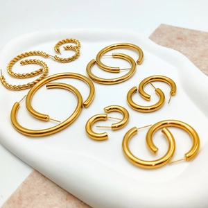 Set of gold-plated stainless steel hoop earrings in various sizes and textures on a tray