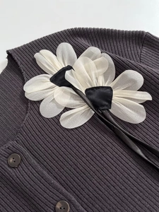 Detail of charcoal grey ribbed knit cardigan featuring white organza flower appliques