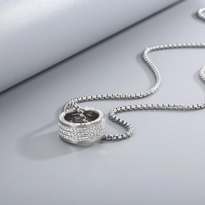 Detail of silver layered ring pendant with inlaid crystals on a steel box chain