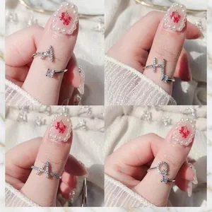 Dettaglio di bracciali intrecciati in argento vintage e anelli con lettere regolabili