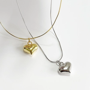 Polished gold and silver heart necklaces with sleek snake chains on a white background