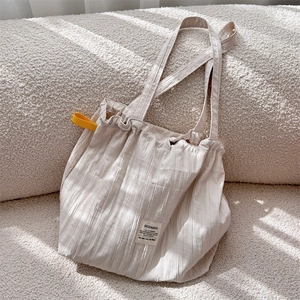 Detail of minimalist cream pleated tote bag with yellow strap and SOZAKKA woven label