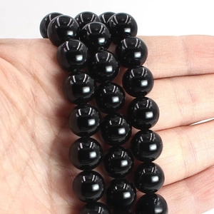 Close-up of polished black agate round beads held in hand for DIY jewelry making