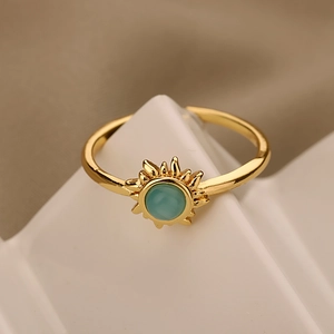 Macro shot of gold sun-shaped ring with green cat eye stone on geometric stand