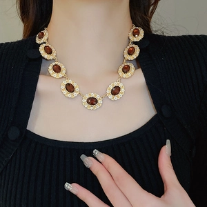 Macro shot of gold necklace with oval amber gemstones and zircon halo on model