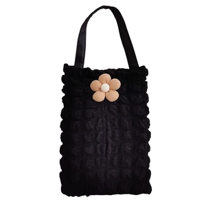Detail of black popcorn texture tote bag with a pink 3D flower and sturdy handles
