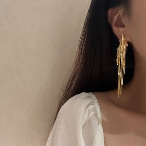 Dettaglio di orecchini vintage a nappa dorata indossati da una modella in stile lusso
