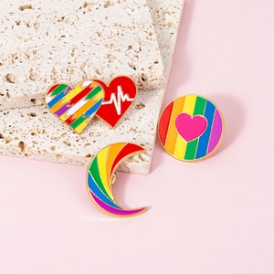 Rainbow enamel pin set with heart and moon shapes on elegant stone display stands