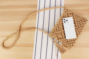 Detailed view of bohemian woven cotton bag with tassels and a phone for size scale