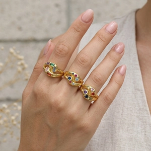 Detail of three wavy gold rings with colorful multi-shape zircon stones on a model hand
