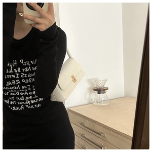 Detail of a white crossbody handbag paired with a black graphic long-sleeve tee shirt