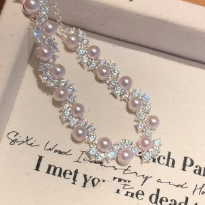 Elegant wave-shaped pink pearl bracelet with shimmering zircon accents on white gift box