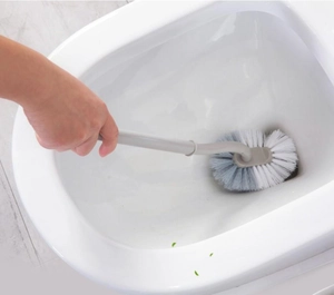 Detail of toilet brush with curved long handle cleaning hard to reach rim areas