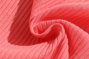 Macro shot of coral pink ribbed cotton fabric showing soft texture and elastic weave
