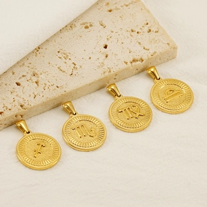 Detail of four golden 18K zodiac pendants including Sagittarius and Scorpio on fabric