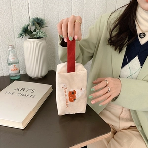 Detail der Cord-Kosmetiktasche mit floraler Hasenbestickung und rotem Griff
