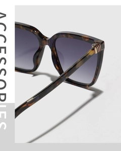 Detailed close-up of tortoise shell frame sunglasses with golden hinge and gradient lens