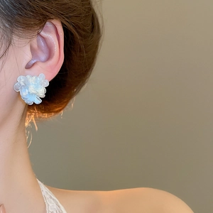 Close-up of elegant creamy white flower stud earrings worn on model for a graceful look