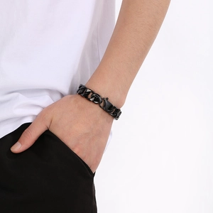 Close-up of a black titanium steel Cuban link bracelet with a lobster clasp on a wrist